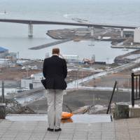 Britain\'s Prince William offers a silent prayer for the victims of the March 11, 2011, earthquake and tsunami as he looks over land raked by the tsunami from a hilltop in Ishinomaki, Miyagi Prefecture, on March 1. | AFP-JIJI