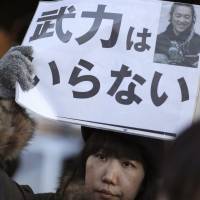 A protester outside Prime Minister Shinzo Abe’s office on Feb. 1 holds a sign reading “We do not need armed forces,” after Islamic State extremists executed journalist Kenji Goto. Islamic State propaganda may be drawing Western coalition into 'holy war'