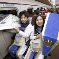 A couple in costumes pose on the first Kagayaki bullet train to depart from JR Kanazawa Station bound for Tokyo on Saturday morning after the Hokuriku Shinkansen Line opened for business. | KYODO