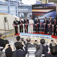 Bureaucrats and officials perform a ribbon-cutting ceremony on a platform at JR Nagano Station on Saturday to mark the opening of the Hokuriku Shinkansen Line. | KYODO