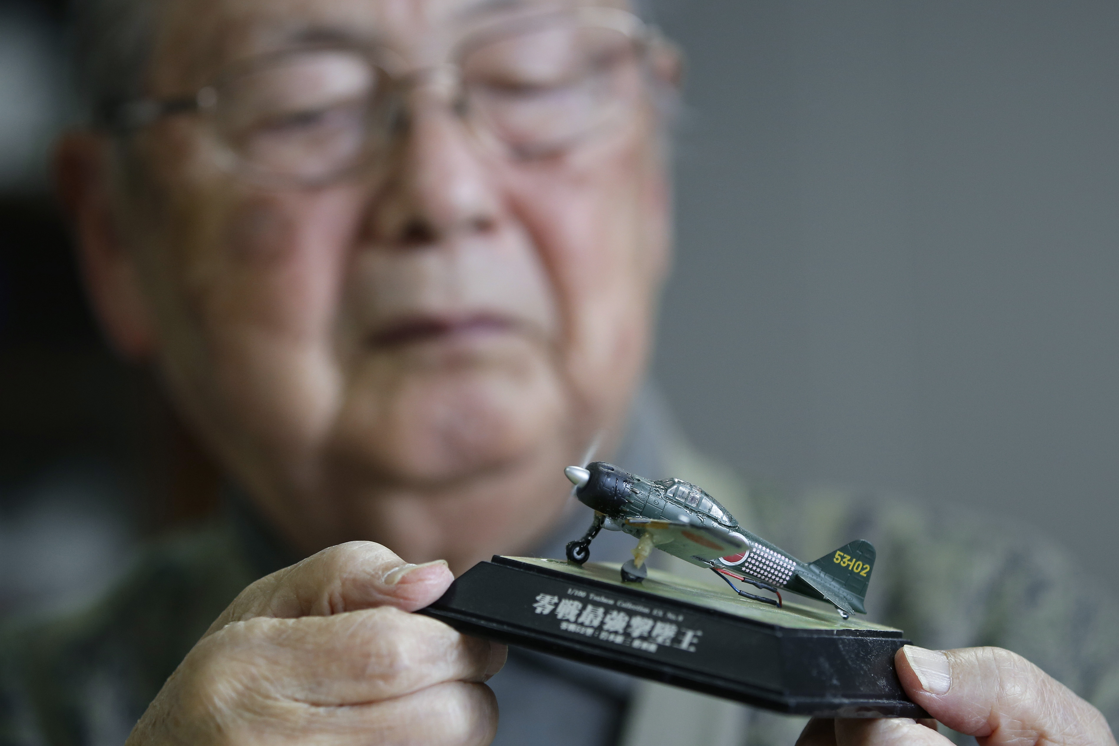 Hisashi Tezuka, a former kamikaze pilot, holds a 1/100-scale plastic model he built of the Type-52 Zero fighter, during an interview at his home in Yokohama on Feb. 19. | BLOOMBERG