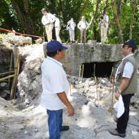 Palau President Tommy Remengesau (in vest) observes on Wednesday the work of a Japanese team searching for the remains of soldiers who died in battle on Peleliu Island, Palau. | KYODO