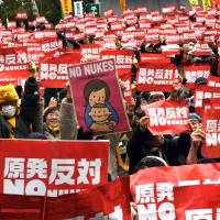 Protesters hold up placards at a rally Sunday in Tokyo to denounce atomic power plants. | AFP-JIJI