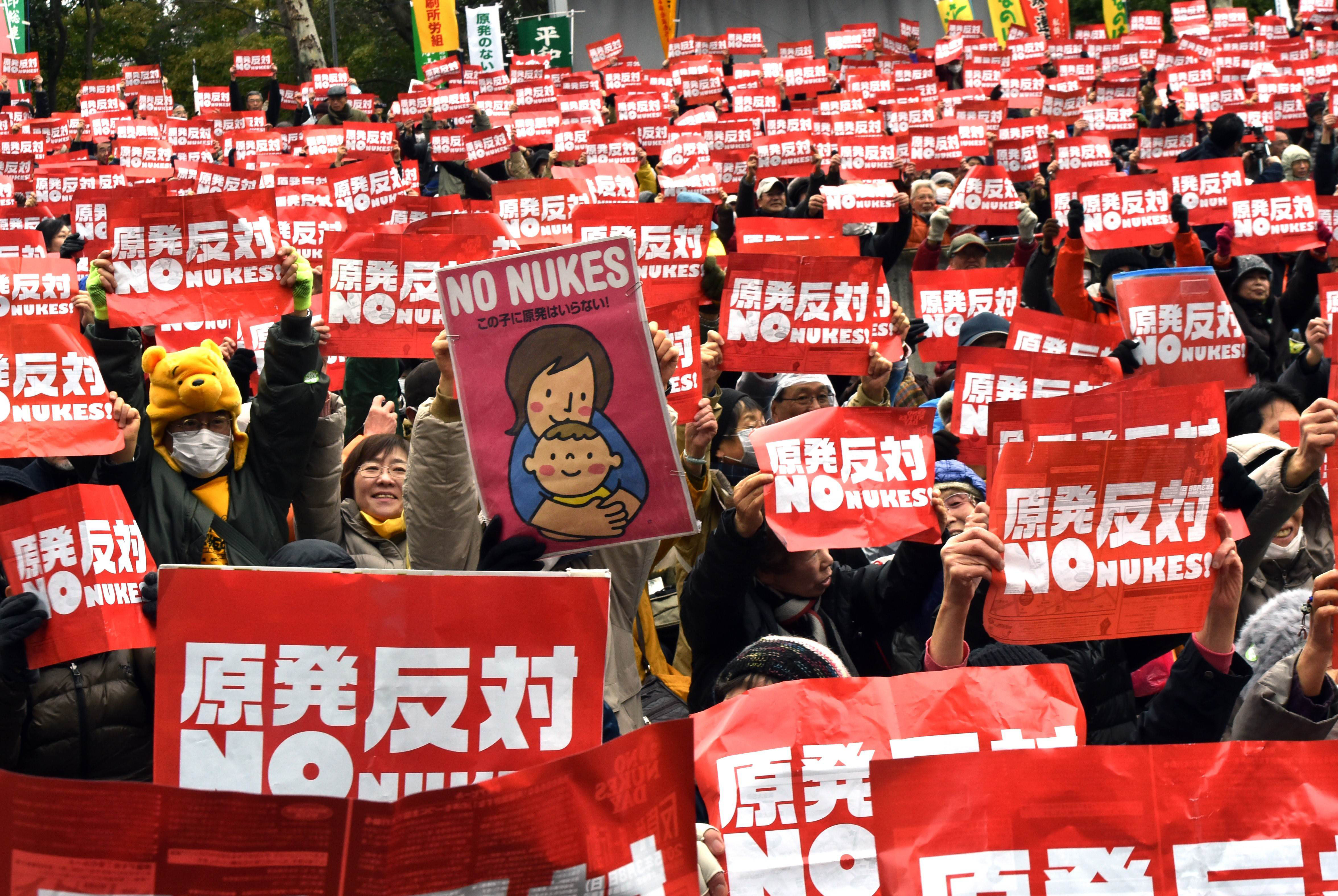 Protesters hold up placards at a rally Sunday in Tokyo to denounce atomic power plants. | AFP-JIJI