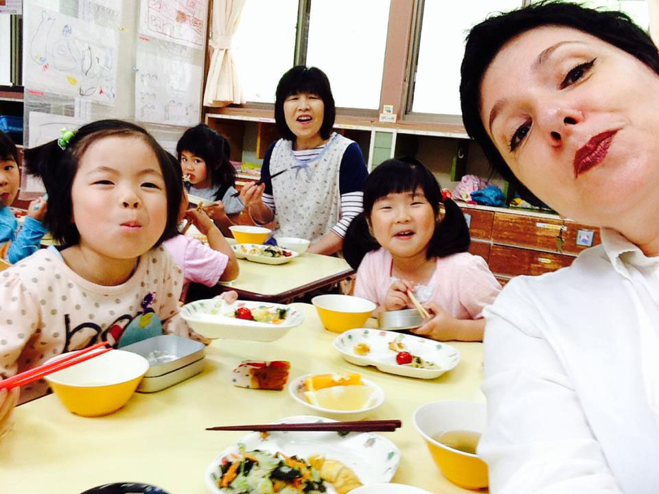 Rikuzentaka Global PR Director Amya Miller (right) eats with children at Yahagi Preschool in Rikuzentakata, Iwate Prefecture, last summer. | BLOOMBERG