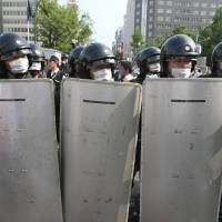 Police officers wearing protective gear stand guard during a protest against the Group of Eight summit in Sapporo in July 2008. | BLOOMBERG