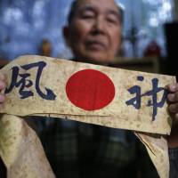 Author Katsumoto Saotome, 82, a survivor of the Great Tokyo Air Raid in 1945, holds a headband with the word \"kamikaze\" on it during an interview at his home in Tokyo last Wednesday. | REUTERS
