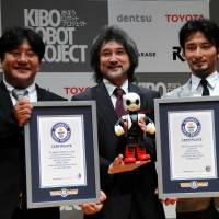 Kirobo, the robot that went to the International Space Station, celebrates its two Guinness World Records: the first companion robot in space, and the robot to have held a conversation at the highest altitude. Seen on Friday in Tokyo are Fuminori Kataoka of the Product Planning Group of Toyota Motor Corp. (center), Dentsu Inc.\'s Yorichika Nishijima (left) and University of Tokyo robotics scientist Tomotaka Takahashi. | SATOKO KAWASAKI