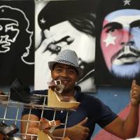 A vendor gives a thumbs up as he sells shoes and paintings of Cuba\'s revolutionary hero Ernesto \"Che\" Guevara in Havana on Tuesday, the day President Barack Obama said he will remove Cuba from the list of state sponsors of terrorism. | AP