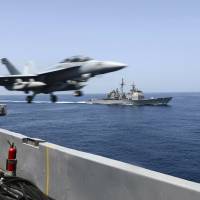 An EA-18G Growler launches from the flight deck of the aircraft carrier USS Theodore Roosevelt (CVN 71) with the guided-missile cruiser USS Normandy (CG 60) alongside during maritime security operations in the Arabian Sea in this U.S. Navy photo taken Tuesday.  The Roosevelt and Normandy will join seven other U.S. warships near Yemen, which is torn by civil strife as Iranian-backed Houthi rebels battle forces loyal to the U.S.-backed president. The warships are also keeping tabs on an Iranian flotilla that may be trying to bring arms to the Houthis. | REUTERS