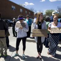 Protesters hold support signs for Freddie Gray outside of Vaughn Greene Funeral Home, during his wake Sunday in Baltimore. Gray died from spinal injuries about a week after he was arrested and transported in a police van. | AP