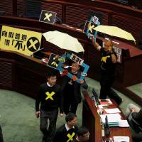 Pro-democracy lawmakers Raymond Chan (second right) chants slogans as he and Albert Chan (right), carrying yellow umbrellas, a symbol of the pro-democracy Occupy Central protest movement, leave to boycott Hong Kong Chief Secretary Carrie Lam during a Legislative Council meeting in the city Wednesday. The Hong Kong government unveiled a long-awaited electoral blueprint for selecting the city\'s next leader to lawmakers on Wednesday, in a plan that reflected China\'s desire for a tightly controlled poll that is likely to rile democracy activists. | REUTERS