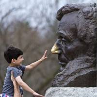 A man lifts up his 6-year-old son so that he can rub the nose on a bust of President Abraham Lincoln outside his tomb in Springfield, Illinois, on April 8. Local legend has it that rubbing the nose brings good luck. | AP