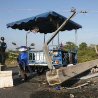 A Thai police officer inspects the site of one of four bomb blasts which hit the restive province of Pattani on Thursday. Rebel groups have mounted an 11-year insurgency demanding autonomy for mainly Muslim regions in Thailand\'s south, bordering Malaysia. | AFP-JIJI