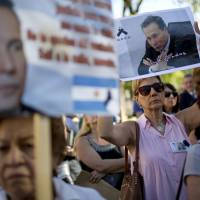 Demonstrators on March 18 hold images of the late prosecutor Alberto Nisman during an act to demand justice after more than a month after his death, outside the courthouse in Buenos Aires. The discovery of a gun in a storage area is raising new questions about the death. Probe into Argentine prosecutor's mystery shooting death turns up his gun in storage