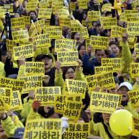 Relatives of the victims of the Sewol disaster and others rally in Seoul on Saturday. The relatives want the government to salvage the sunken ferry and are demanding that the government\'s enforcement ordinance for the special law on the Sewol be discarded. The placards read: \"Discard the enforcement ordinance and salvage the Sewol ferry.\" | AP