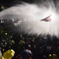 South Korean riot police use a water cannon to spray protesters gathered in front of Gwanghwamun gate, the main entrance to Gyeongbok Palace, during a rally held in Seoul on Saturday. Hundreds of protesters, commemorating the first anniversary of the Sewol ferry disaster, clashed with police in the capital after families of victims were prevented from marching on the presidential Blue House with their demands. | AFP-JIJI