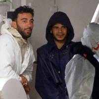 Yunidian Mohammed Ali Malek (left), one of the survivors and understood to be the captain of the boat that overturned Saturday off Libya, and a man identified as Mahmud Bikhit (center) of Syria, another survivor and believed crew member of the boat, stand aboard the Italian Coast Guard vessel Bruno Gregoretti at Boiler Wharf, Senglea, in Malta on Monday. Italian police said Tuesday both were being held over the capsizing of their ship that caused hundreds of migrants locked belowdecks to drown in the Mediterranean\'s deadliest disaster in decades. | AFP-JIJI