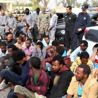 Libyan security forces guard migrants who were detained in Tripoli\'s western neighborhood of Ghut al-Shaal on Tuesday as they were gathering to depart toward Libyan\'s Mediterranean coast hoping to board boats that would take them to Europe. | AFP-JIJI