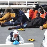 Survivors of the smuggler\'s boat that overturned off Libya rest Tuesday on the deck of the Italian Coast Guard ship Bruno Gregoretti, in Valletta\'s Grand Harbour. | AP