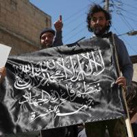 Residents hold a Nusra Front flag during a demonstration celebrating their takeover of Idlib about a month ago, and also calling for the implementation of Shariah law, in the al-Sakhour neighborhood of Aleppo on Friday. | REUTERS