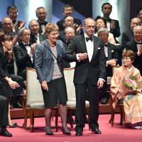 Theodore Friedmann of the United States and his wife are congratulated by the audience after being awarded the Japan Prize in Tokyo on Thursday. Alain Fischer (left) of France and Yutaka Takahashi (right) of Japan were also awarded the annual prize, which is given to people who have contributed to the development of science and technology. | AFP-JIJI