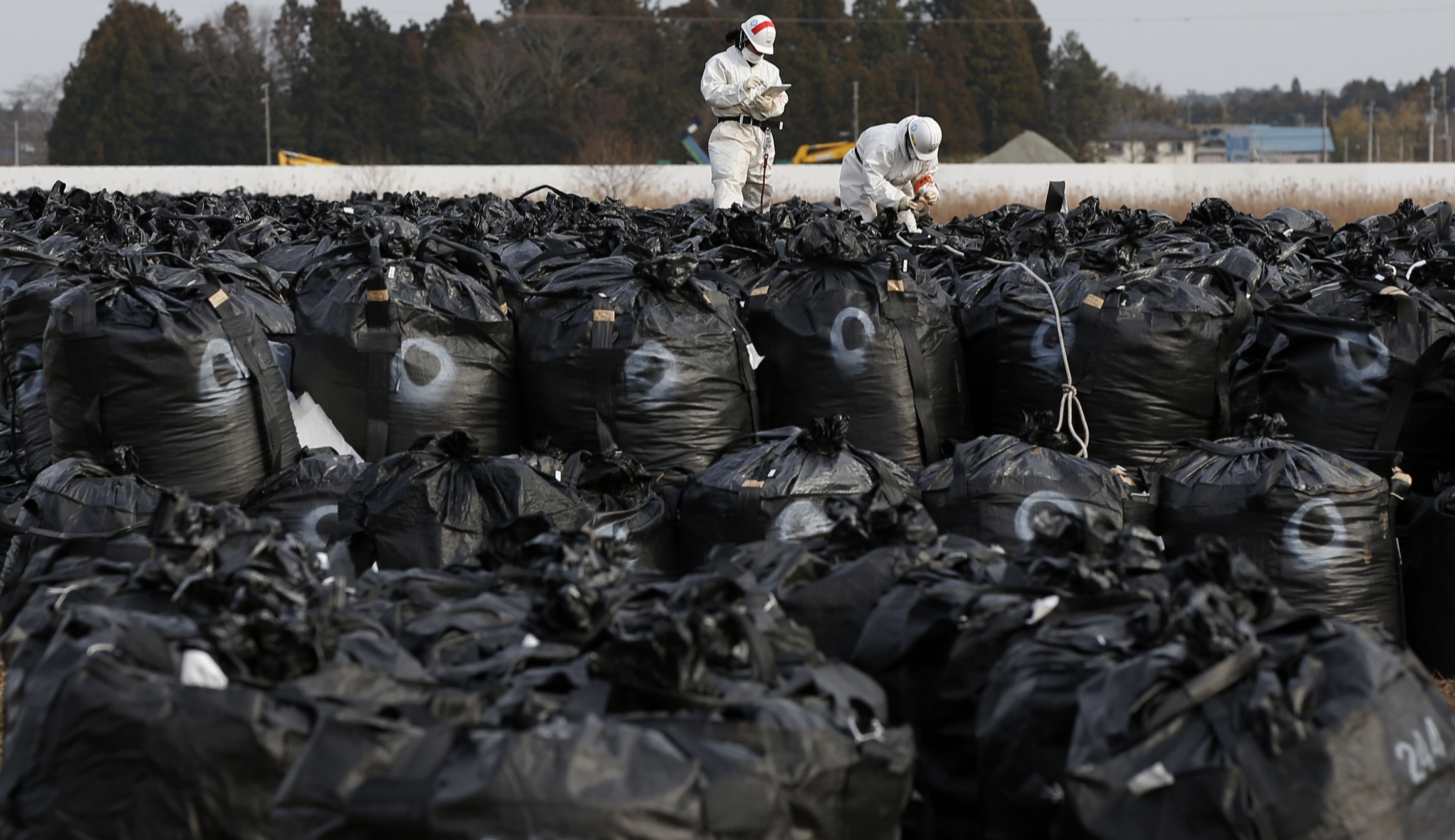 Workers work on bags containing soil, leaves and other debris from the decontamination operation in Tomioka, Fukushima Prefecture, near Tepco's Fukushima No. 2 nuclear power plant, on Feb. 24. | REUTERS