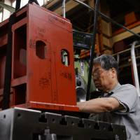 Katumi Takata, chairman of Osaka Machine Tool Co., operates his oldest piece of equipment, a Spiramatic Jigmil made in Michigan more than half a century ago by the DeVlieg Machine Co., in Higashiosaka, Osaka Prefecture, on Tuesday. | BLOOMBERG