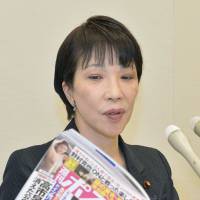 Internal affairs minister Sanae Takaichi holds a copy of the Shukan Post during a news conference Monday in Tokyo. | KYODO