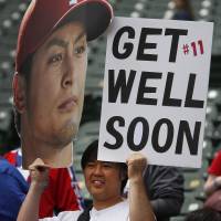 Warm thoughts: Texas Rangers fan Tak Fujita holds a sign in support of pitcher Yu Darvish who was put on the disabled list before the start of the Rangers\' home opener in Texas. | AP