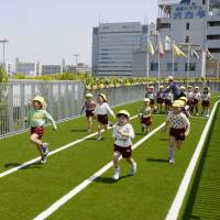 Sprinter Nobuharu Asahara, who won a bronze medal in the men\'s 4x100-meter relay at the 2008 Beijing Olympics, runs with children on the rooftop track of Morinomiya Q\'s Mall Base, a new commercial complex in Osaka, during a preview event on Thursday. The facility opened on Monday and has 49 tenants who offer sports facilities such as a fitness gym, a futsal court and sport gear shops, as well as general merchandise shops. Visitors can jog around the 300-meter rooftop track free of charge before or after shopping. | KYODO