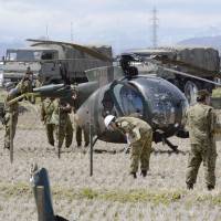 Ground Self-Defense Force personnel examine the wreck of an OH-6D helicopter that made a crash landing in a rice paddy in Sendai on Monday. No one was hurt, but all 46 choppers of the same model have been grounded until the cause of the accident is determined. | KYODO