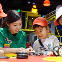 Children build Lego vehicles Tuesday under the guidance of a staffer at a Legoland theme park in Osaka scheduled to open on Thursday. About 100 nursery school kids were invited to attend the media preview. | KYODO