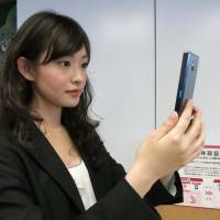 A woman watches the screen on Fujitsu\'s Arrows NX smartphone handset from Docomo, which reads her iris using biometric identification technology. | KAZUAKI NAGATA