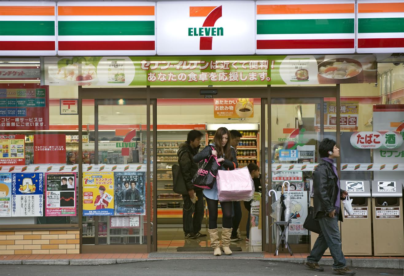 A customer exits a 7-Eleven convenience store in Tokyo in 2010. Convenience stores are undergoing a quiet shift to a higher target demographic, departing from their long-established image as a place for young shoppers. | BLOOMBERG