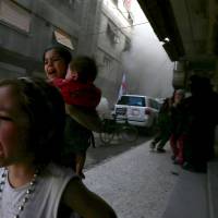 Children run from what activists said was shelling by forces loyal to Syrian President Bashar Assad near the Syrian Arab Red Crescent center in the Douma neighborhood of Damascus on Wednesday. | REUTERS
