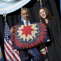 President Barack Obama holds a quilt given to him after speaking at a commencement ceremony at Lake Area Technical Institute in Watertown, South Dakota, on Friday. South Dakota was the last of the 50 states Obama has visited as president. | AFP-JIJI