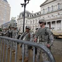 National Guardsmen stand in front of City Hall during a protest for Freddie Gray on Thursday, in Baltimore. Police have handed prosecutors their report on Gray\'s death while in custoday, an incident that sparked riots earlier in the week. | AP
