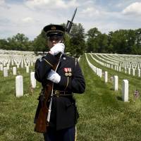 A member of an honor guard holds his rifle as the motorcade carrying U.S. President Barack Obama departs after he participated in the Memorial Day observance at Arlington National Cemetery in Arlington, Virginia, Monday. | REUTERS