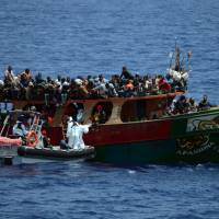 This handout picture taken and released by the French Navy (Marine Nationale) on Wednesday shows members of the French Navy crew of the Commandant Birot patrol ship taking part in a rescue operation of 297 migrants aboard the Afandina fishing boat, in the Mediterranean Sea, some 300 km southeast of Italy. | MARINE NATIONALE / AFP-JIJI