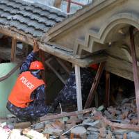 Rescue team officials and a sniffer dog search for survivors at a collapsed home in Kathmandu on Tuesday after a magnitude-7.3 earthquake hit devastated Nepal. | AFP-JIJI