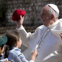 Pope Francis takes a cap from a girl scout during his visit to Regina Pacis parish church in Ostia in the outskirts of Rome, Sunday. | AP