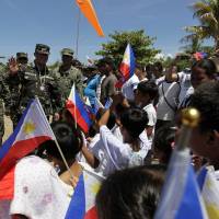 Philippines military chief Gen. Gregorio Catapang Jr. (second, left) waves as residents welcome him in Pagasa Island (Thitu Island) at the Spratly group of islands in the South China Sea, west of Palawan, on Monday. Catapang visited the island amid escalating tensions with China over its alleged reclamation and building activities in the disputed South China Sea. The Spratlys are considered a potential Asian flashpoint, and claimant nations have expressed alarm as China has embarked on massive reclamation activity. | RITCHIE B. TONGO / POOL / AFP-JIJI