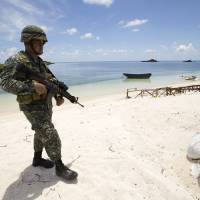 Philippine soldier Tychico Octobre patrols a beach in Pagasa Island (Thitu Island) on Monday. | RITCHIE B. TONGO / POOL / AFP-JIJI