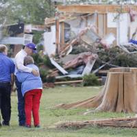 Charmaine Foraker is hugged by her son, Harlan, as she and her other son, Craig Foracker (second from left) arrive at the scene of the family farmstead near Bentley, Kansas, that was destroyed by a tornado Wednesday. | TRAVIS HEYING / THE WICHITA EAGLE VIA AP