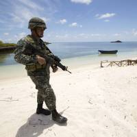 A Philippine soldier patrols the island of Pagasa in the Spratly chain on Monday in the South China Sea. | AFP-JIJI