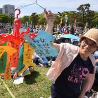 An activist holds up anti-war messages Sunday at Yokohama\'s Rinko Park, where 30,000 people gathered for a Constitution Day rally to protest moves to revise the supreme law. | SATOKO KAWASAKI