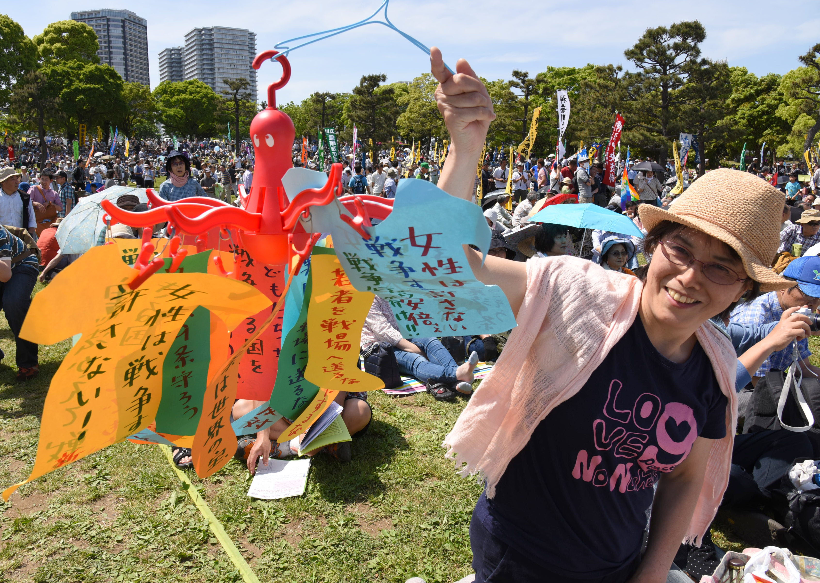 An activist holds up anti-war messages Sunday at Yokohama's Rinko Park, where 30,000 people gathered for a Constitution Day rally to protest moves to revise the supreme law. | SATOKO KAWASAKI