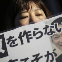 A supporter of journalist Kenji Goto holds a placard with the slogan \"Do not make an enemy\" outside the Prime Minister\'s Official Residence in Tokyo on Feb. 1 after an online video came to light which purported to show Goto\'s execution. | AP