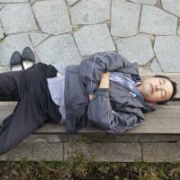 A man sleeps on a bench in Tokyo in November 2010. | ISTOCK
